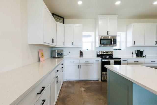 kitchen featuring white cabinetry, stainless steel appliances, and light stone countertops