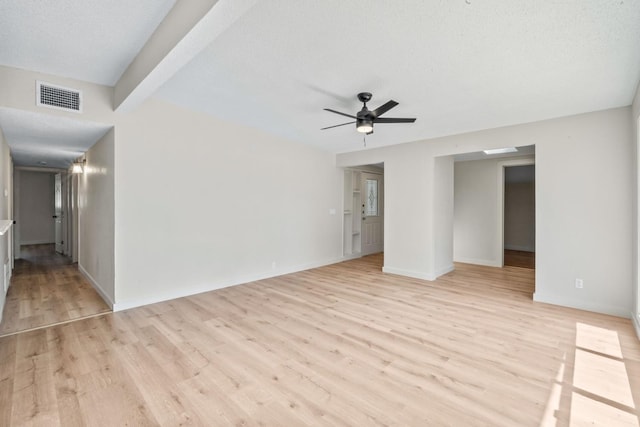 empty room featuring beam ceiling, ceiling fan, a textured ceiling, and light hardwood / wood-style floors