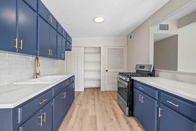 kitchen with light hardwood / wood-style floors, sink, blue cabinetry, and stainless steel range with gas stovetop