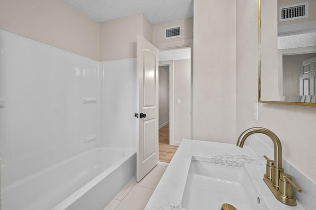 bathroom featuring vanity, shower / tub combination, and a textured ceiling