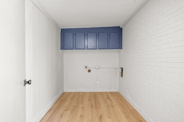 laundry room with hookup for a washing machine, light hardwood / wood-style flooring, cabinets, and brick wall