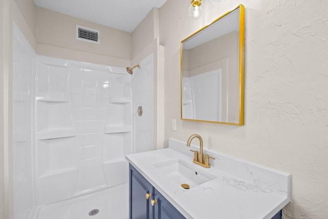 bathroom featuring vanity, a textured ceiling, and a shower