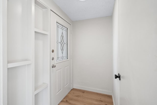 doorway with a textured ceiling and light wood-type flooring