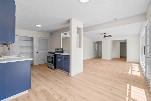 kitchen featuring sink, light hardwood / wood-style flooring, ceiling fan, a textured ceiling, and gas range