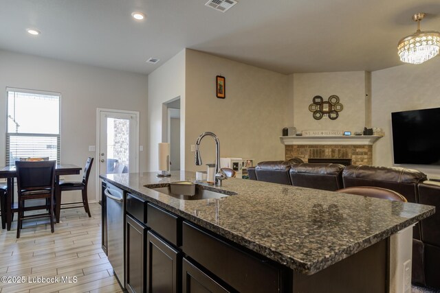 10423 Winfield Ave, Lubbock, TX 79424 - kitchen featuring a sink, dark stone countertops, light wood-type flooring, an island with sink, and open floor plan