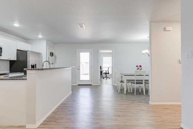 8413 10th Pl, Lubbock, TX 79416 - kitchen with stainless steel refrigerator with ice dispenser, dark stone counters, light wood-type flooring, baseboards, and white cabinetry