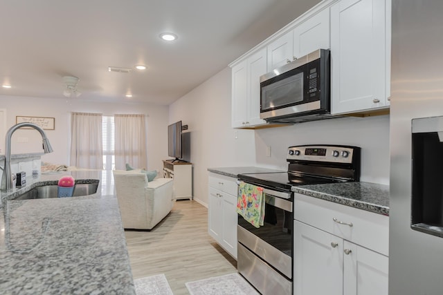 8413 10th Pl, Lubbock, TX 79416 - kitchen featuring appliances with stainless steel finishes, a sink, white cabinetry, recessed lighting, and light wood finished floors