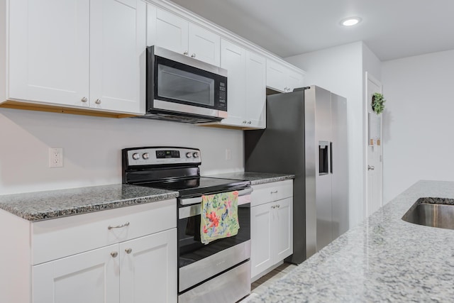 8413 10th Pl, Lubbock, TX 79416 - kitchen featuring appliances with stainless steel finishes, light stone countertops, white cabinets, recessed lighting, and wood finished floors