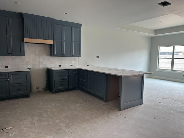 kitchen featuring a tray ceiling, decorative backsplash, gray cabinetry, and kitchen peninsula