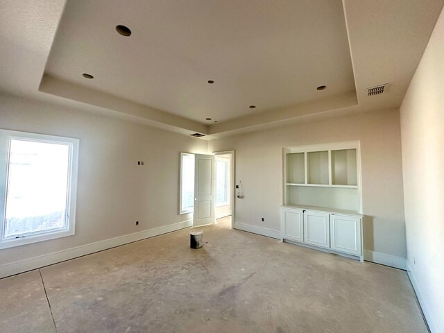 empty room featuring built in shelves and a raised ceiling