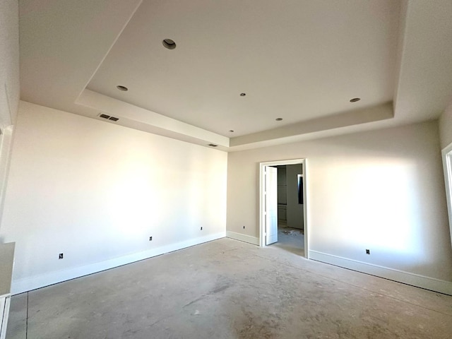 unfurnished room featuring a raised ceiling and concrete floors