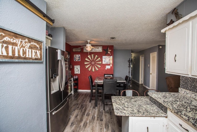 kitchen with stainless steel fridge with ice dispenser, white cabinets, dark hardwood / wood-style flooring, ceiling fan, and light stone counters