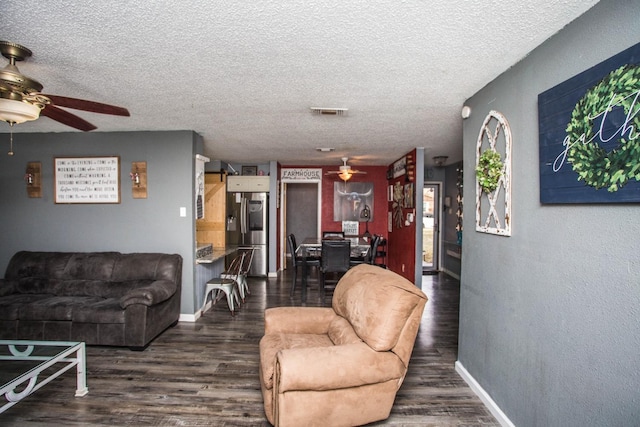 living room featuring dark hardwood / wood-style flooring, a textured ceiling, and ceiling fan