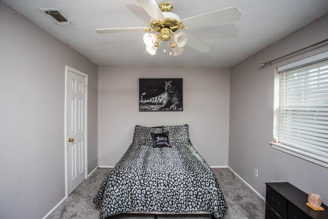 bedroom with ceiling fan, carpet, and a textured ceiling