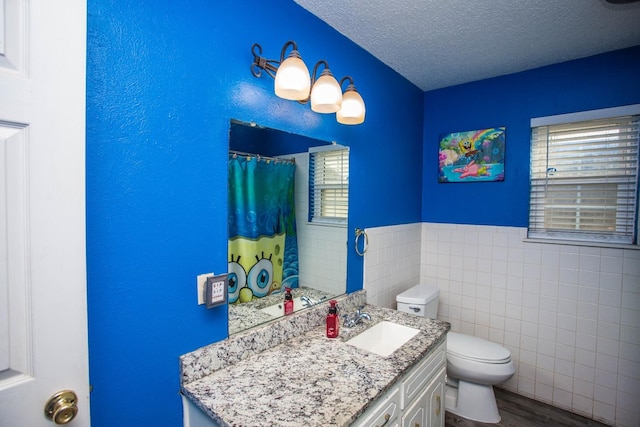 bathroom with tile walls, a shower with shower curtain, vanity, a textured ceiling, and toilet