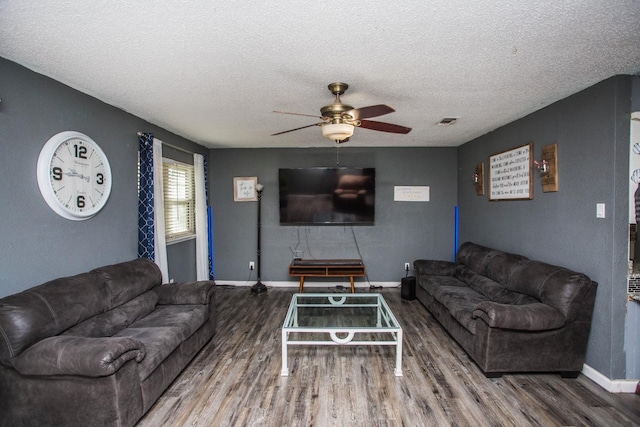 living room featuring ceiling fan, wood-type flooring, and a textured ceiling