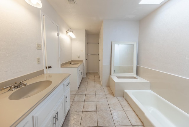 bathroom with vanity, a tub to relax in, tile patterned flooring, and a skylight