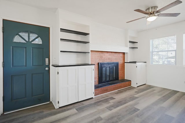 foyer entrance with hardwood / wood-style flooring, ceiling fan, and a fireplace