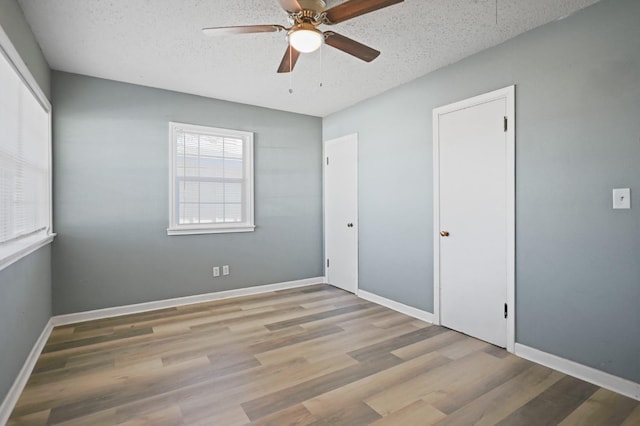 unfurnished bedroom with light wood-type flooring, a textured ceiling, and ceiling fan