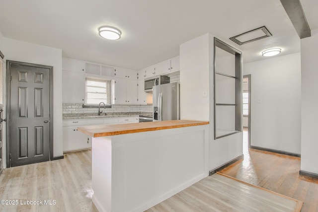 2014 60th St, Lubbock, TX 79412 - kitchen featuring appliances with stainless steel finishes, light wood-style floors, butcher block counters, and decorative backsplash
