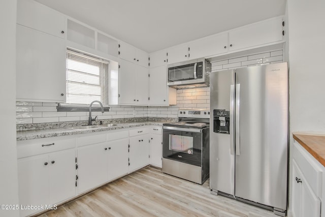 2014 60th St, Lubbock, TX 79412 - kitchen with appliances with stainless steel finishes, tasteful backsplash, white cabinets, light countertops, and light wood-style floors