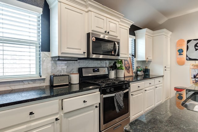 kitchen with tasteful backsplash, stainless steel appliances, white cabinets, and lofted ceiling