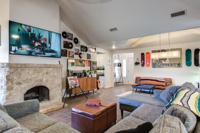 living room with hardwood / wood-style flooring, lofted ceiling, and a fireplace