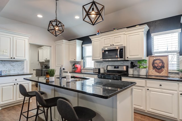 kitchen featuring pendant lighting, appliances with stainless steel finishes, sink, and a kitchen island with sink