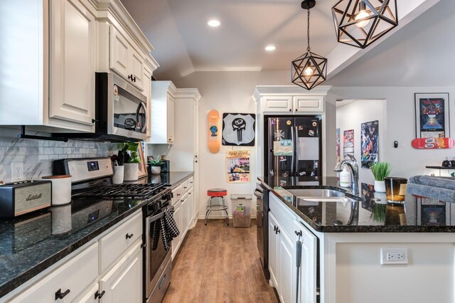 kitchen featuring sink, hanging light fixtures, appliances with stainless steel finishes, white cabinets, and backsplash