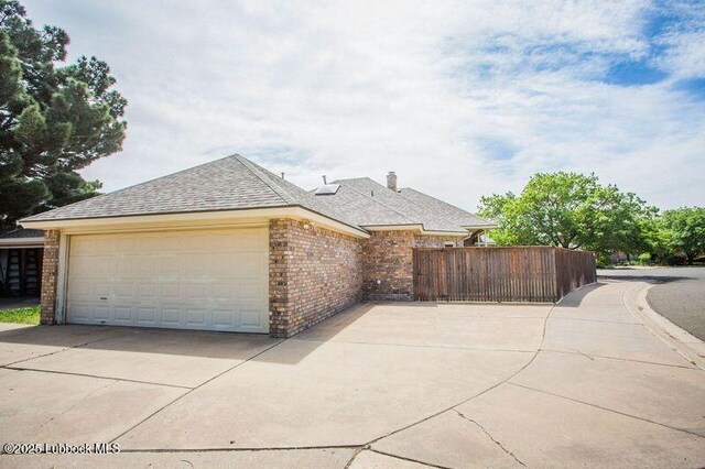 5110 1st Pl, Lubbock, TX 79416 - view of side of property featuring brick siding, concrete driveway, a shingled roof, and a garage