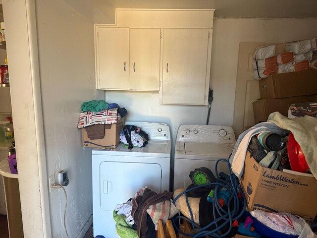 clothes washing area with cabinets and washing machine and clothes dryer