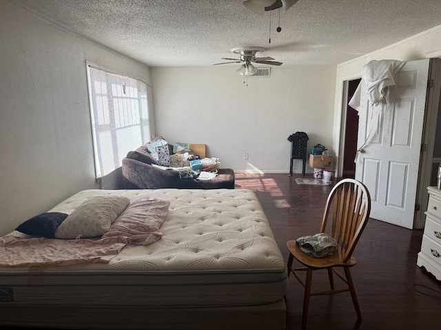 bedroom featuring dark hardwood / wood-style flooring, ceiling fan, and a textured ceiling