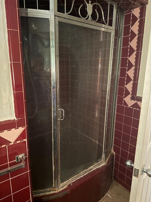 bathroom featuring bath / shower combo with glass door and tile patterned floors