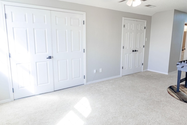 unfurnished bedroom featuring carpet, baseboards, multiple closets, and visible vents