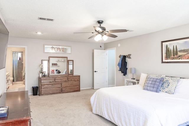 carpeted bedroom featuring ensuite bathroom, a textured ceiling, visible vents, baseboards, and a ceiling fan