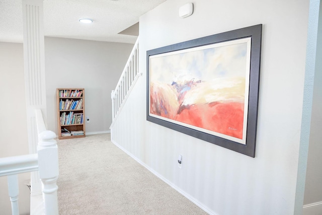 hallway featuring baseboards, carpet flooring, and a textured ceiling