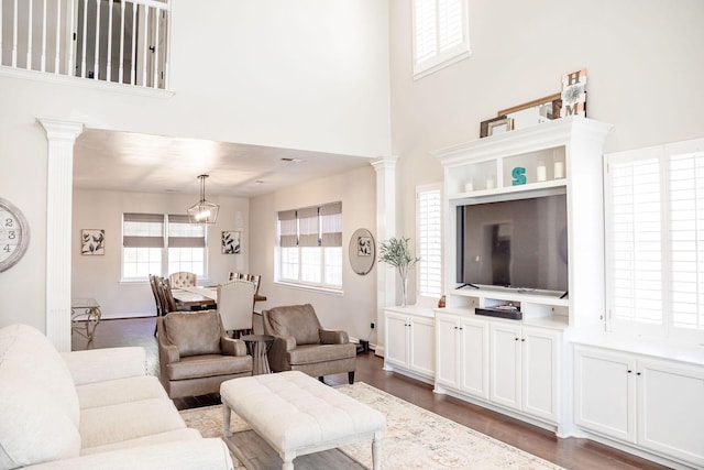 living area with ornate columns, a high ceiling, and dark wood-type flooring