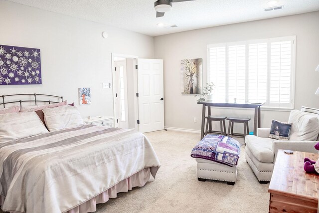 carpeted bedroom with baseboards, a textured ceiling, visible vents, and a ceiling fan