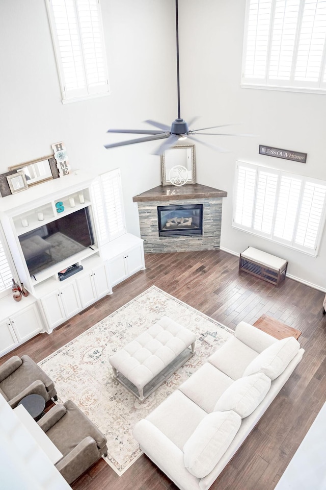 living room with wood finished floors, a glass covered fireplace, and a ceiling fan