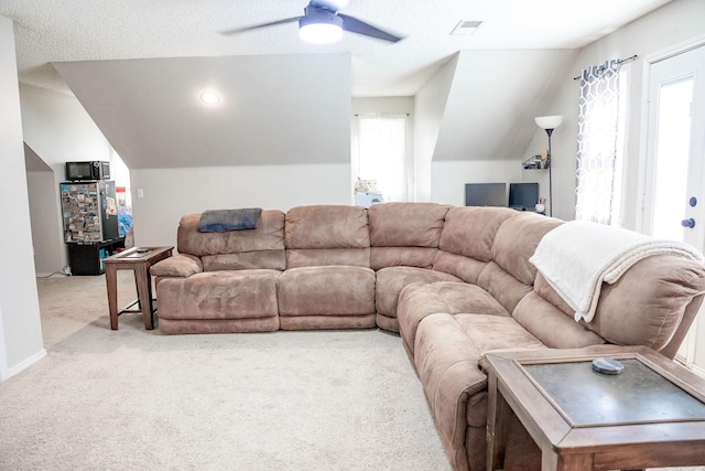 living room featuring lofted ceiling, visible vents, a ceiling fan, and light carpet
