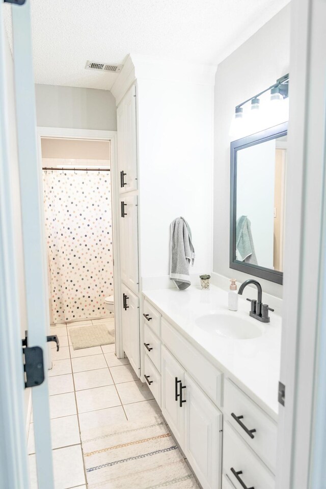 full bathroom with toilet, curtained shower, vanity, tile patterned flooring, and visible vents