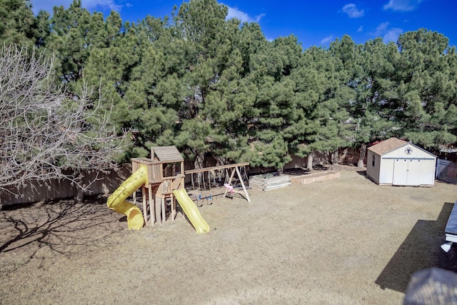 view of jungle gym featuring an outdoor structure, a fenced backyard, a shed, and a garden