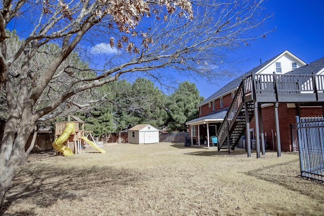 view of yard with a shed, an outbuilding, fence, and stairway