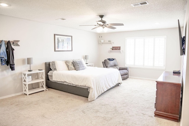 bedroom with carpet floors, a textured ceiling, baseboards, visible vents, and ceiling fan