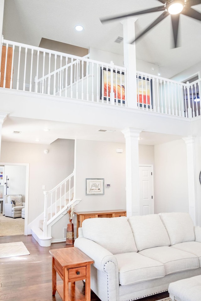 living room featuring a high ceiling, wood finished floors, stairway, and ceiling fan