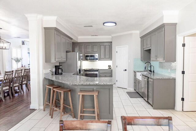 kitchen with gray cabinetry, a peninsula, and stainless steel appliances