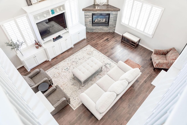 living room with a glass covered fireplace, baseboards, and wood finished floors