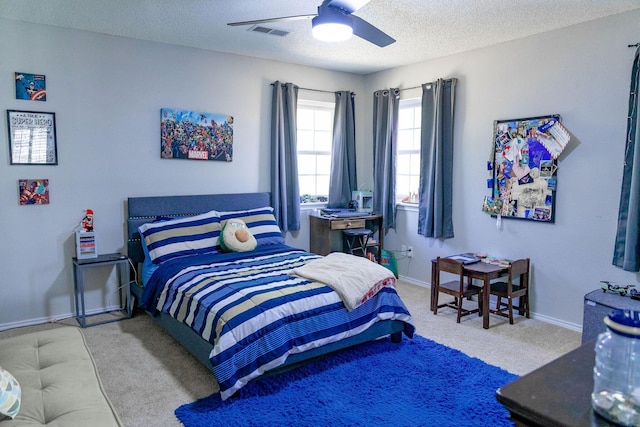carpeted bedroom featuring baseboards, visible vents, ceiling fan, and a textured ceiling
