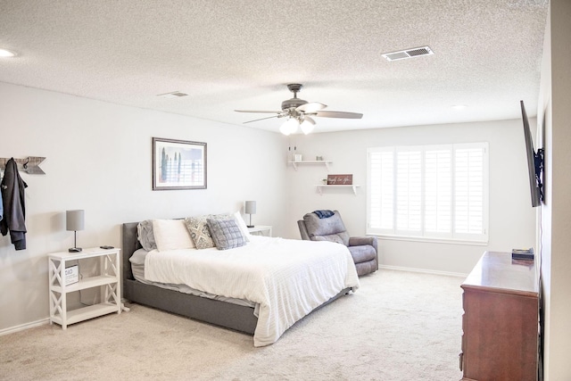 carpeted bedroom featuring baseboards, a textured ceiling, visible vents, and a ceiling fan
