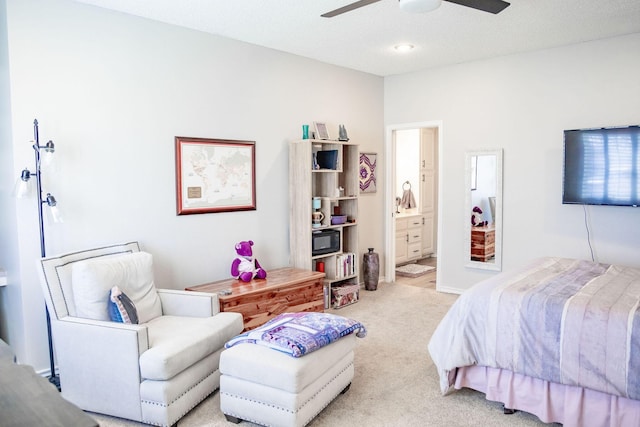 bedroom featuring light colored carpet, baseboards, ensuite bath, and a ceiling fan